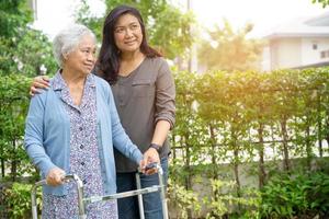 aiutare e curare la donna anziana o anziana asiatica anziana usa il camminatore con una buona salute mentre cammina al parco in una felice vacanza fresca. foto