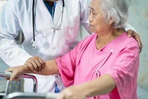 il medico aiuta e cura la donna anziana asiatica anziana o anziana usa il camminatore con una buona salute mentre cammina in ospedale. foto