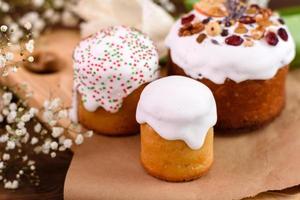 torte festive con glassa bianca, noci e uvetta con uova di Pasqua sulla tavola festiva foto