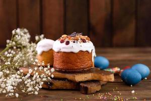 torte festive con glassa bianca, noci e uvetta con uova di Pasqua sulla tavola festiva foto