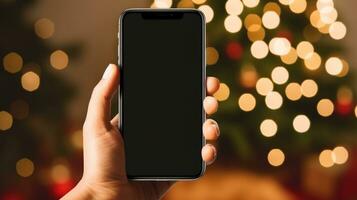 un' mano Tenere un' Telefono con un' Natale albero sfondo foto