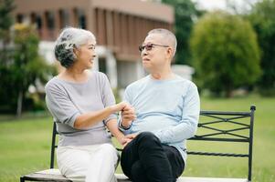 asiatico anziano coppia avendo un' bene volta. essi ridendo e sorridente mentre seduta all'aperto a il parco. bello anziano coppia foto