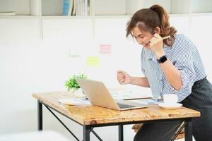 bellissimo giovane adolescente asiatico attività commerciale donna utilizzando computer il computer portatile con mani su nel vincitore è un' gesto, contento per essere con successo festeggiare realizzazione successo. foto