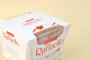 Raffaello caramelle su beige sfondo. Raffaello è un' sferico Noce di cocco mandorla confezione quello italiano fabbricante ferrero portato per il mercato nel 1990 foto