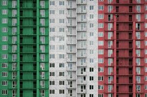 Italia bandiera raffigurato nel dipingere colori su multipiano residenziale edificio sotto costruzione. strutturato bandiera su mattone parete sfondo foto