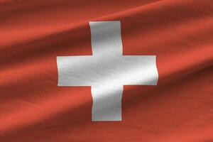 Svizzera bandiera con grande pieghe agitando vicino su sotto il studio leggero al chiuso. il ufficiale simboli e colori nel bandiera foto