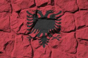 Albania bandiera raffigurato nel dipingere colori su vecchio pietra parete avvicinamento. strutturato bandiera su roccia parete sfondo foto