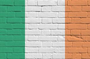 Irlanda bandiera raffigurato nel dipingere colori su vecchio mattone parete. strutturato bandiera su grande mattone parete opere murarie sfondo foto