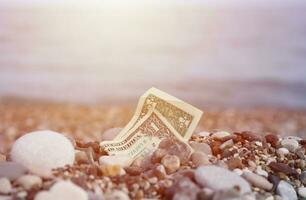 uno dollaro metà coperto con il giro rocce menzogna su spiaggia foto