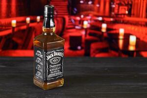 Kharkov, Ucraina - febbraio 14, 2021 Jack daniel n.7 whisky bottiglia su di legno tavolo con rosso bar interno su sfondo. elite alcool foto