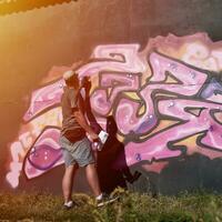 giovane caucasico maschio graffiti artista disegno grande strada arte pittura nel blu e rosa toni foto