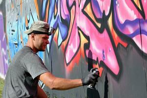 giovane caucasico maschio graffiti artista disegno grande strada arte pittura nel blu e rosa toni foto