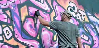 giovane caucasico maschio graffiti artista disegno grande strada arte pittura nel blu e rosa toni foto