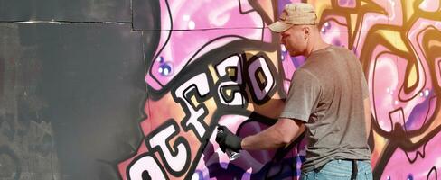 giovane caucasico maschio graffiti artista disegno grande strada arte pittura nel blu e rosa toni foto