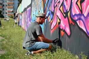 giovane caucasico maschio graffiti artista disegno grande strada arte pittura nel blu e rosa toni foto