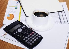 tazza di caffè e calcolatrice con pagina del libro vuota sul tavolo di lavoro con documento foto