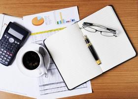 promemoria aziendale vuoto con occhiali e tazza di caffè e calcolatrice e documento sul piano di lavoro per il concetto di business foto