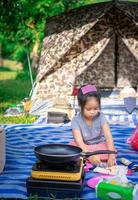 piccola ragazza asiatica che fa colazione davanti alla tenda mentre va in campeggio? foto