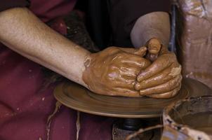 mani di un vasaio che forma argilla foto