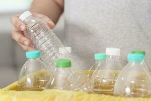 casa riciclare eco verde zero concetto uomo lancio vuoto plastica bottiglia nel raccolta differenziata bidone con giallo spazzatura borse a casa foto