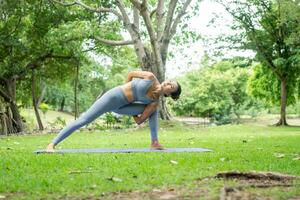 ritratto di un' giovane donna fare yoga nel il giardino per un' allenamento. concetto di stile di vita fitness e sano. asiatico donne siamo praticante yoga nel il parco. foto