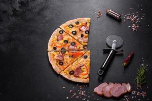 pizza fresca e deliziosa fatta in un forno a focolare con olive, peperoncino e prosciutto foto