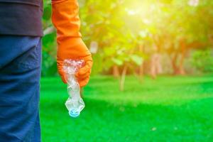 mano dell'uomo volontario che raccoglie una bottiglia di plastica foto