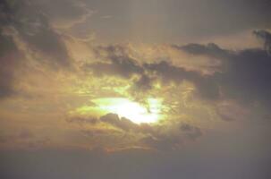 cielo tramonto scenario, sfondo se è il caldo tonalità di un' Alba o tramonto, scintillante riflessione di il sole su il nuvole, il cielo e nuvole avere il energia per ispirare sentimenti di soggezione e Meraviglia foto