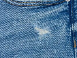 frammento di blu jeans tessuto con un' buco, pieno telaio, vicino su foto