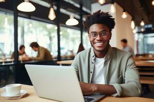 ritratto di allegro nero maschio alunno apprendimento in linea nel caffè negozio, giovane africano americano uomo studi con il computer portatile nel bar, fare compiti a casa foto