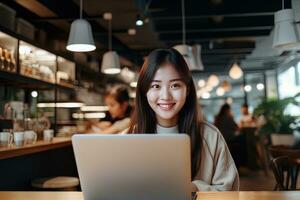 ritratto di contento asiatico femmina alunno apprendimento in linea nel caffè negozio, giovane donna studi con il computer portatile nel bar, fare compiti a casa foto