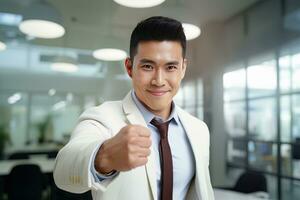 asiatico uomo d'affari mostrando un' combattente posa, maschio imprenditore gesti raccolta pugni nel moderno ufficio, lotte un' problema, celebrare successo e raggiungimento obiettivi. foto
