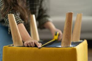 asiatico donna se stesso riparazione mobilia rinnovamento utilizzando attrezzatura per Fai da te riparazione mobilia seduta su il pavimento a casa foto