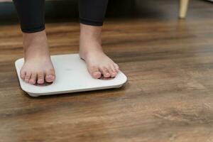 Grasso dieta e scala piedi in piedi su elettronico bilancia per peso controllo. misurazione strumento nel chilogrammo per un' dieta controllo. foto