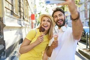 contento giovane coppia assunzione un' autoscatto mentre mangiare ghiaccio crema nel il città foto