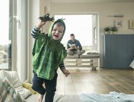 contento ragazzo nel un' costume giocando con giocattolo figura a casa foto