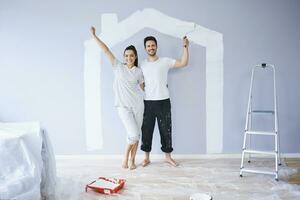 ritratto di allegro coppia pittura nel nuovo appartamento con Casa forma su parete foto