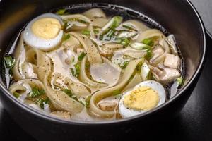 zuppa calda deliziosa fresca con pasta e uova di quaglia in un piatto nero