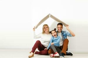 contento famiglia seduta su di legno pavimento. padre, madre e bambino avendo divertimento insieme. in movimento Casa giorno, nuovo casa e design interno concetto foto