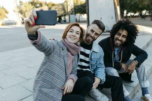 tre contento amici seduta all'aperto assunzione un' autoscatto foto