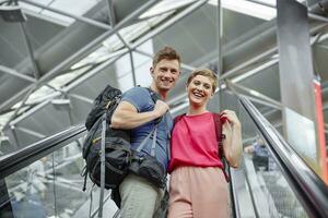 contento coppia su scala mobile a il aeroporto foto