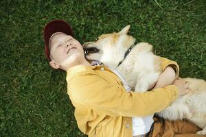 ragazzo con gallese corgi pembroke dire bugie su prato foto