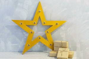 regalo scatola avvolto nel mestiere carta con oro nastro e stelle su grigio pietra foto