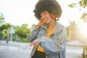 contento giovane donna con afro pettinatura danza nel il città foto