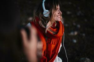 bellissimo donna ascoltando per musica nel foresta durante tramonto foto