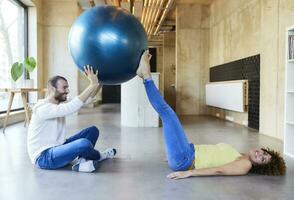 contento uomo e donna praticante con fitness palla nel moderno ufficio foto