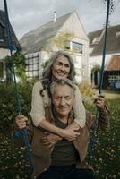 contento donna Abbracciare una persona anziano uomo su un' swing nel giardino foto