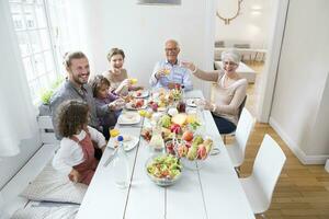 contento esteso famiglia avendo pranzo a casa foto