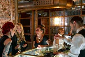 sorridente amici parlando mentre seduta a bar contatore nel pub foto