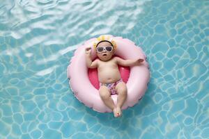carino bambino nel occhiali da sole rilassante su gonfiabile giocattolo squillare galleggiante nel nuoto piscina foto
